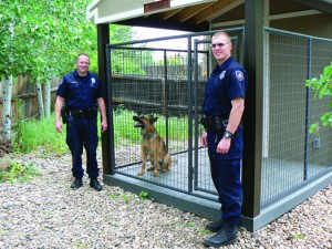 The “christening” of K-9 Koda’s newly built “Kastle” at the residence of Officer John Jones.  Officer Jones is on the left, Officer Brent Kieffer is on the right, and K-9 Koda sits in his new home looking at his “Dad”.