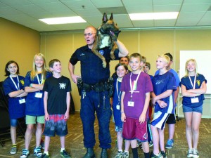 Taken at the Junior Police Academy held at Mission Hills Church in June 2014. The photo illustrates Officer Brent Kieffer and K-9 Sabor demonstrating advanced training technique utilized when K-9 must be placed in an overhead search area such as an attic.  Note that the Officer’s right hand is on K-9 Sabor’s back leg as it rests on the duty belt, an example of the high level of trust the canine has in the handler.